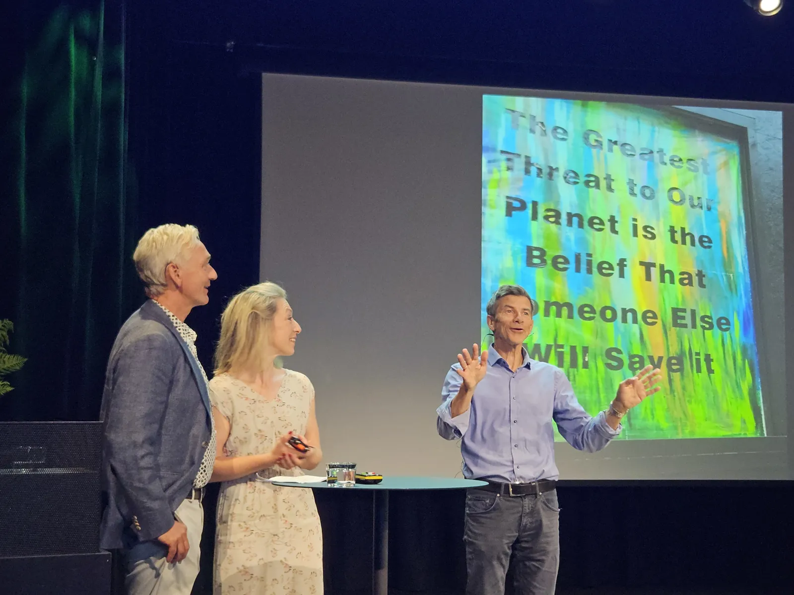 En mann og en kvinne som snakker med en mann foran en projektorskjerm