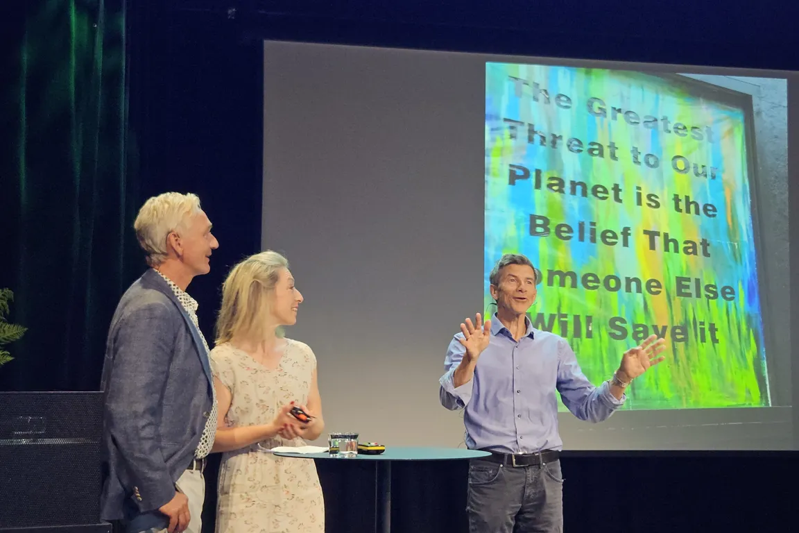 En mann og en kvinne som snakker med en mann foran en projektorskjerm