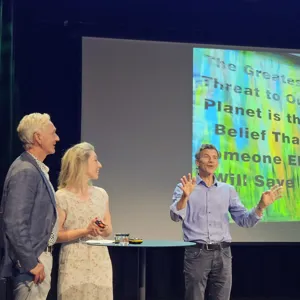 En mann og en kvinne som snakker med en mann foran en projektorskjerm