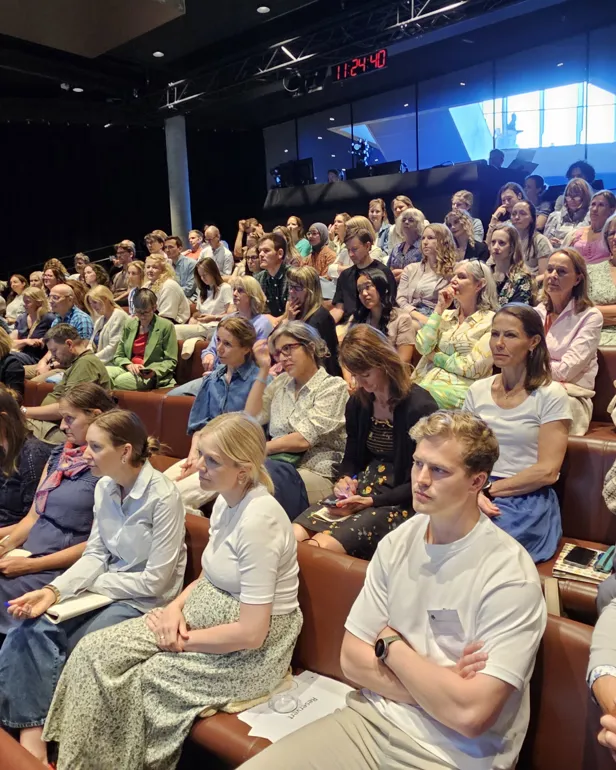 En stor gruppe mennesker som sitter i et rom