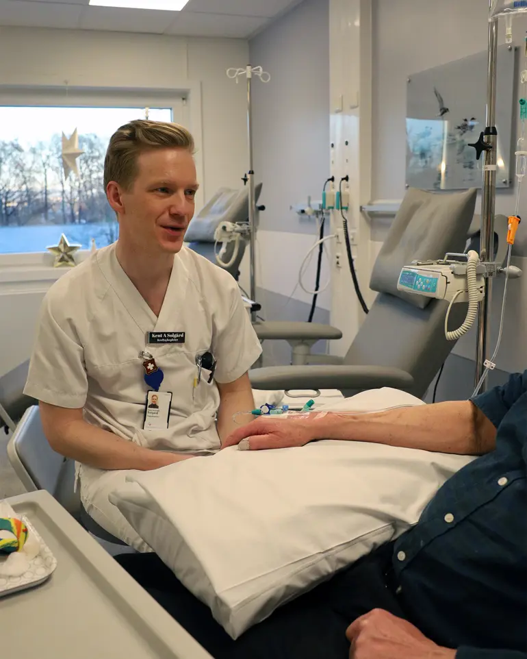 En mann som sitter i en sykehusseng
