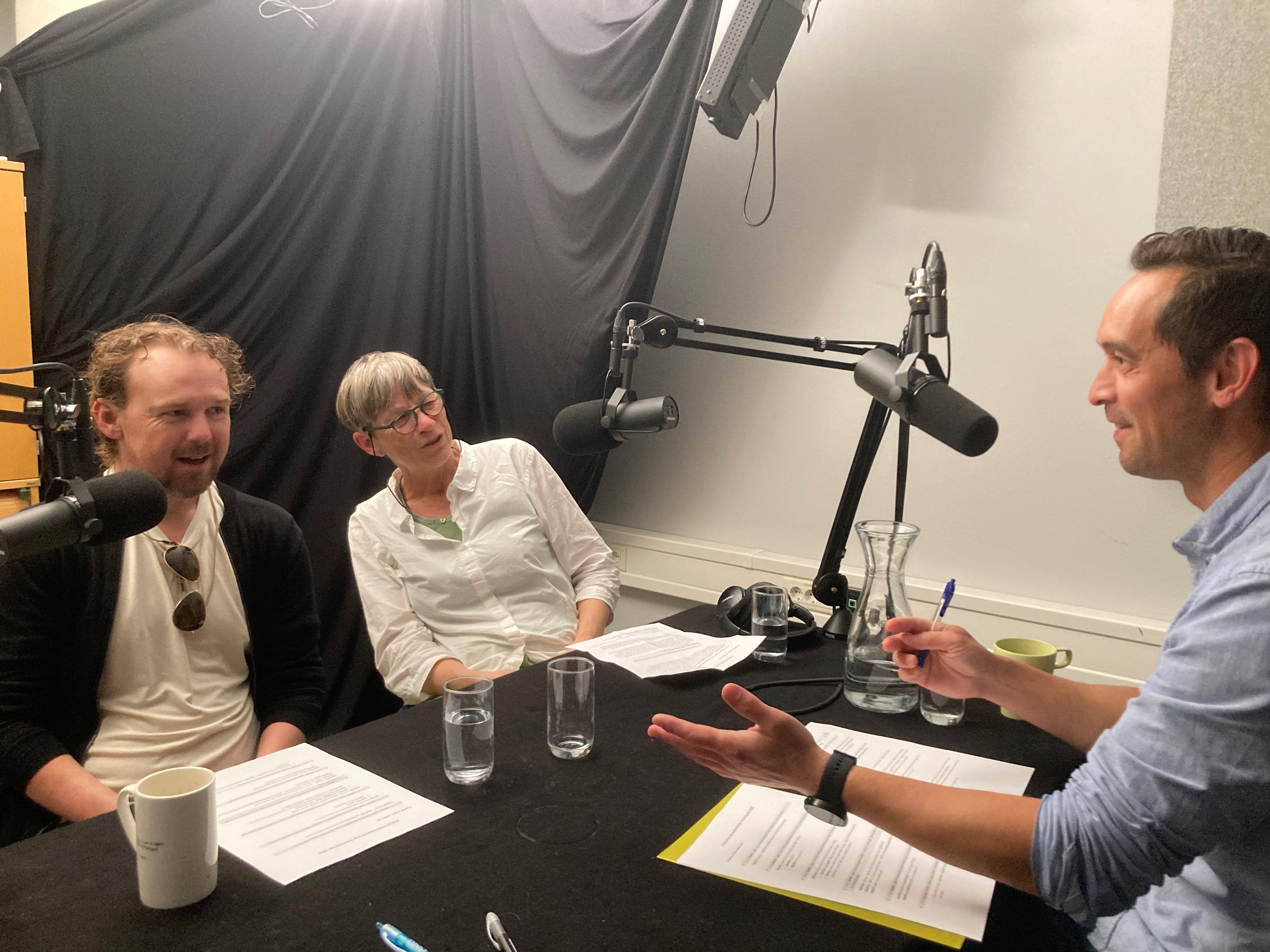 En gruppe mennesker som sitter ved et bord med mikrofoner