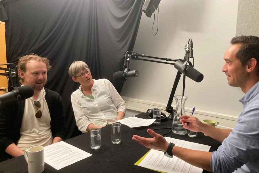 En gruppe mennesker som sitter ved et bord med mikrofoner