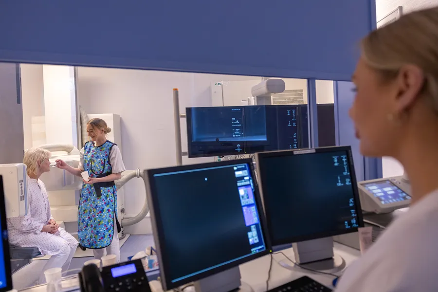 En gruppe mennesker i et rom med datamaskiner