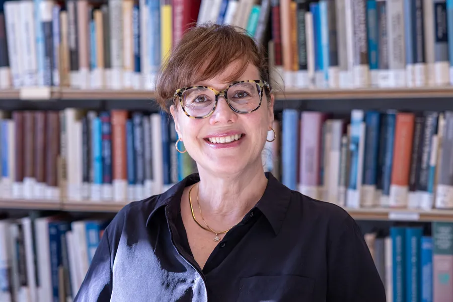 En mann som smiler foran en bokhylle