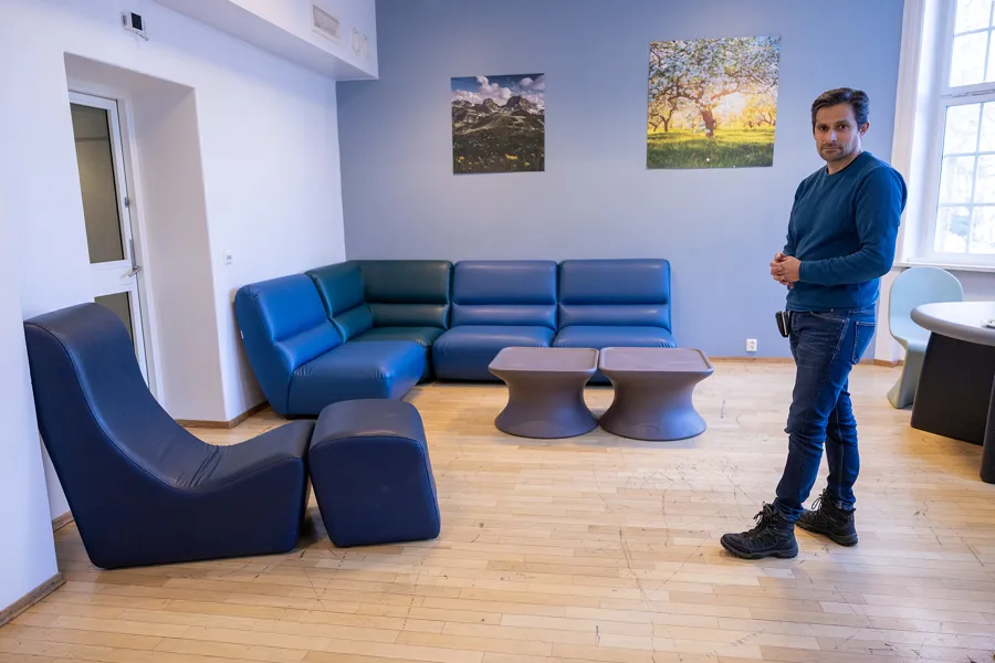 En person som står i et rom med blå sofaer