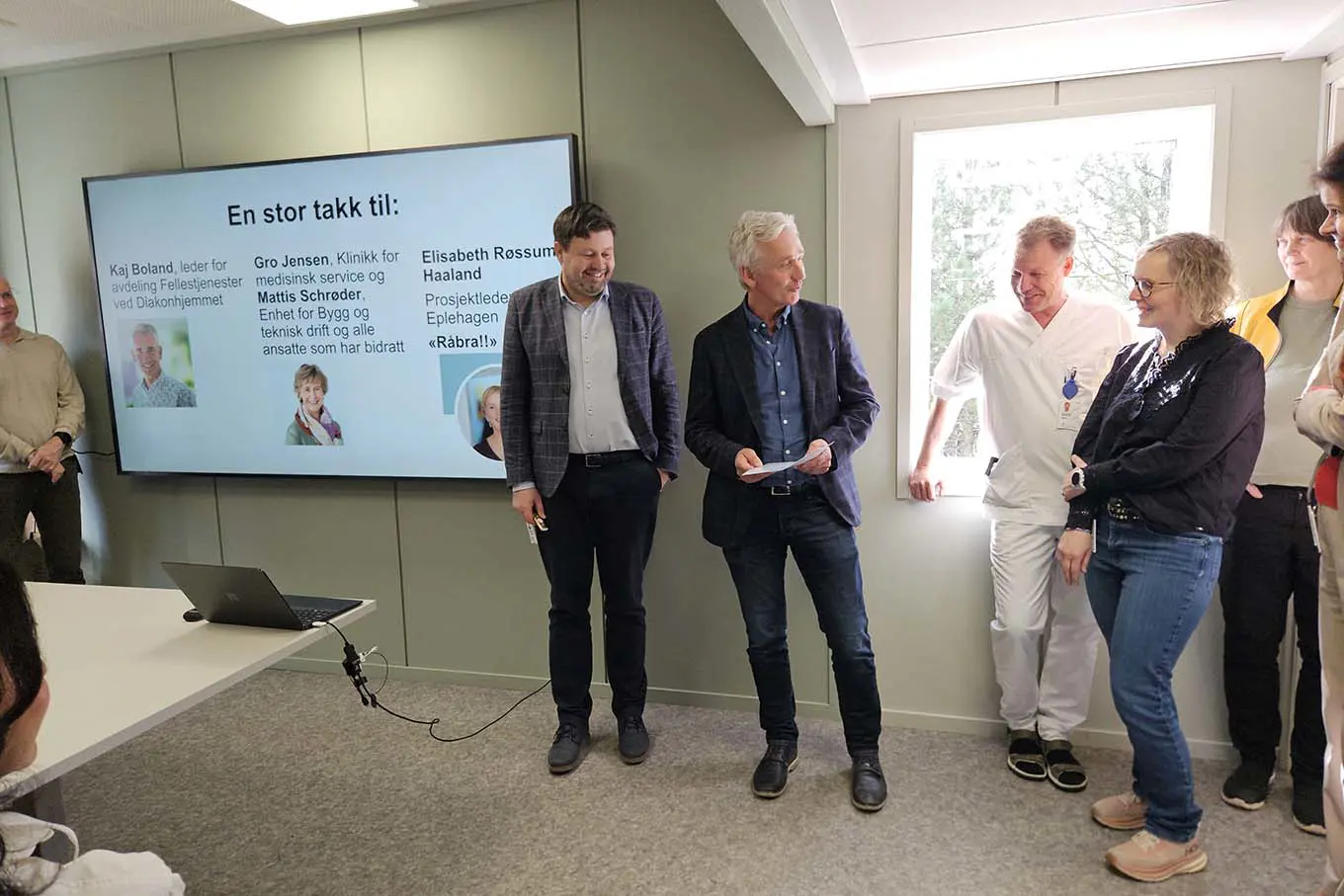 En gruppe mennesker som står foran et projektorlerret