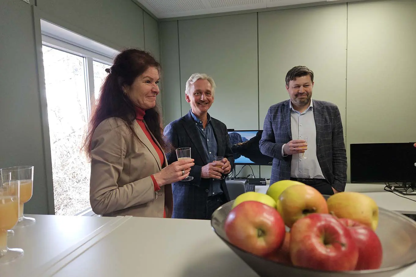 En gruppe mennesker som står rundt et bord med epler og drikke