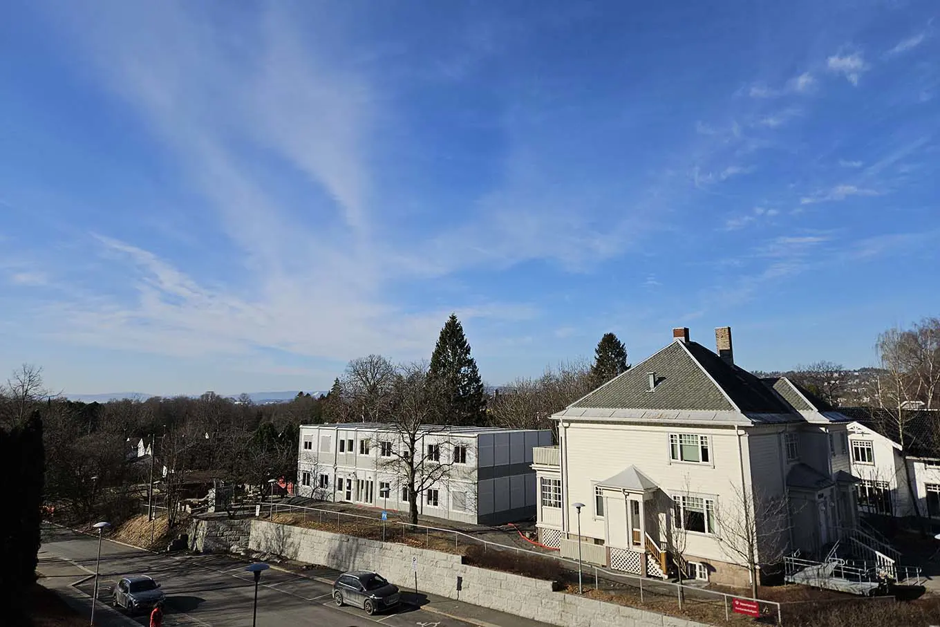 En hvit bygning med parkeringsplass