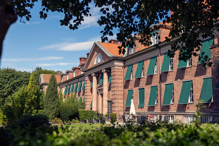 En stor murbygning med grønne lister