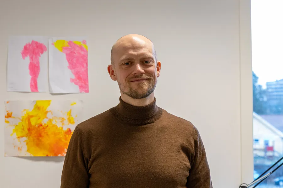 En mann som står foran en vegg med kunst på