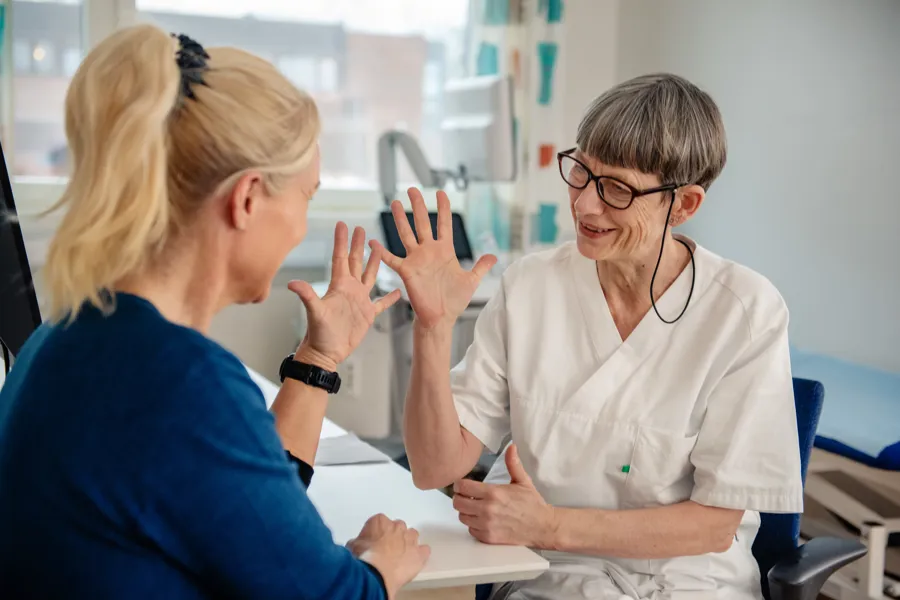 En dame som viser frem hendene til en behandler
