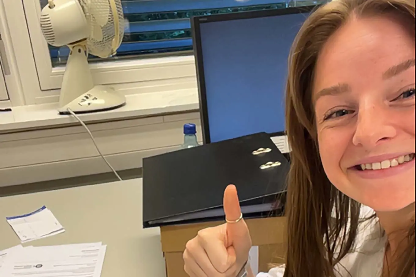 En kvinne som smiler og peker på et nettbrett