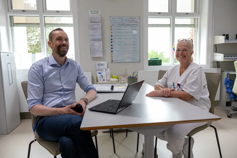 En mann og en kvinne som sitter ved et bord med en bærbar PC