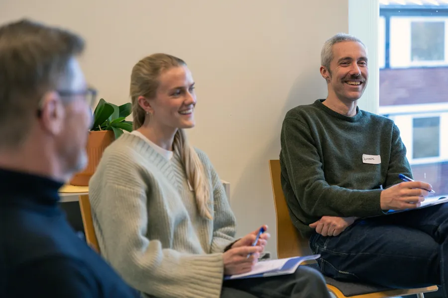 Noen få mennesker som sitter i stoler