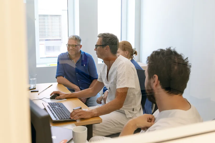 En gruppe mennesker som sitter rundt et bord og ser på en bærbar datamaskin