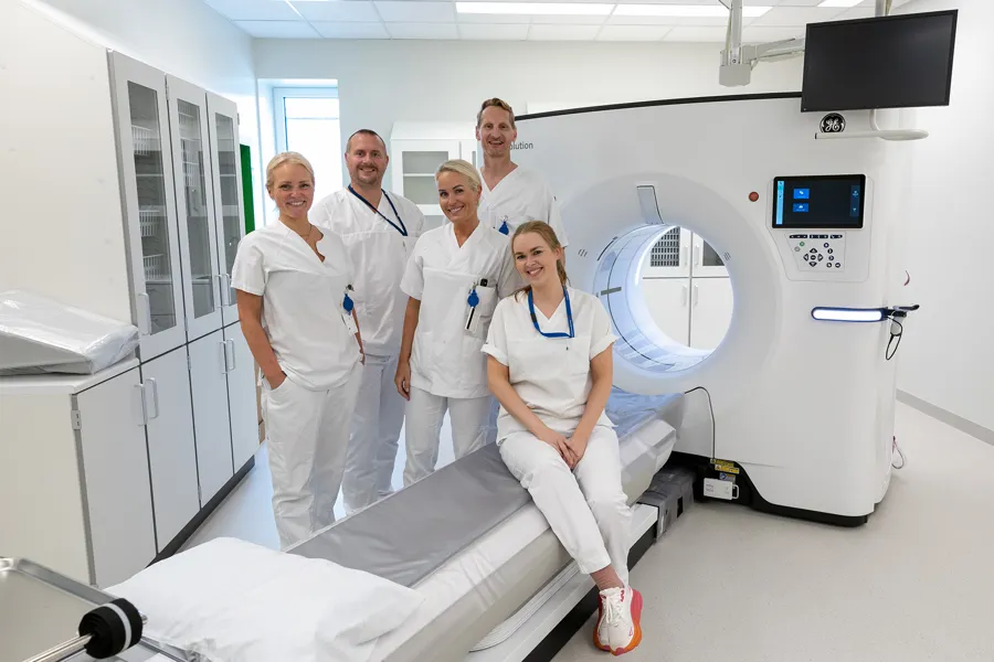 En gruppe mennesker i hvite laboratoriefrakker som står foran en medisinsk maskin