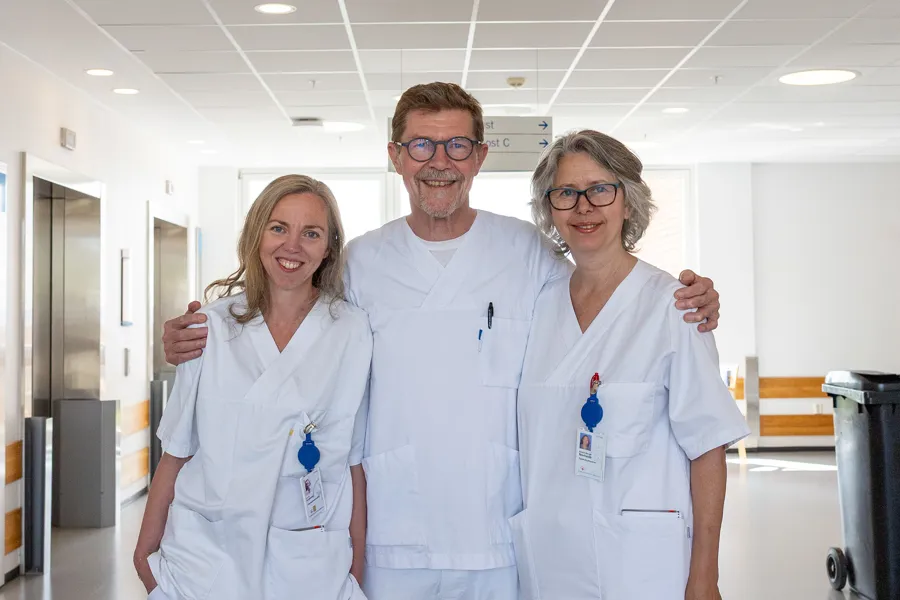 En gruppe mennesker iført hvite laboratoriefrakker og står i et rom