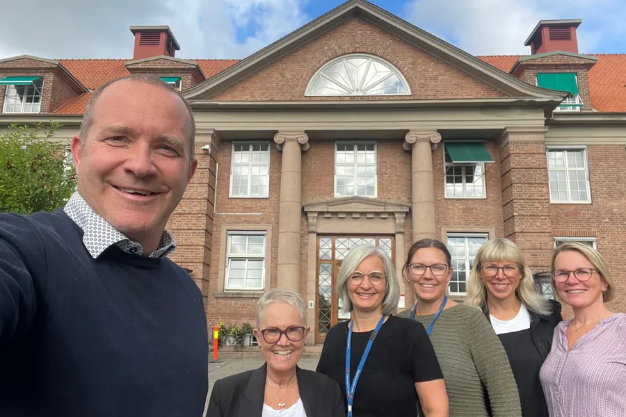 En gruppe mennesker som poserer for et bilde foran en bygning