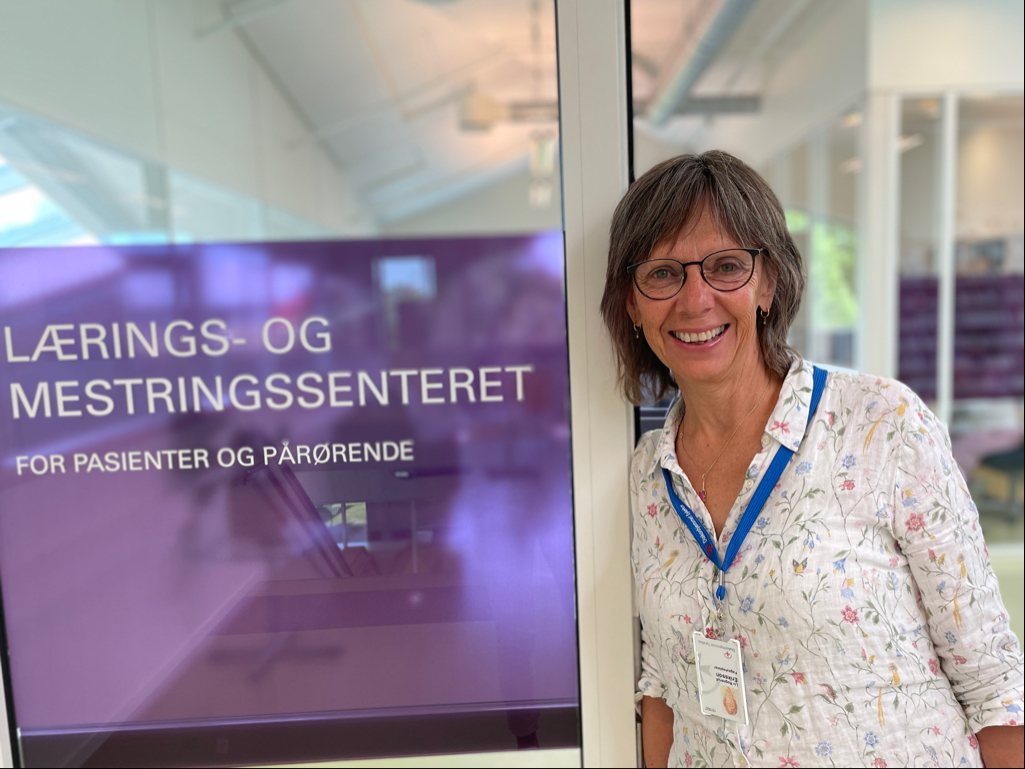 En smilende dame lener seg mot en dørkarm på LMS