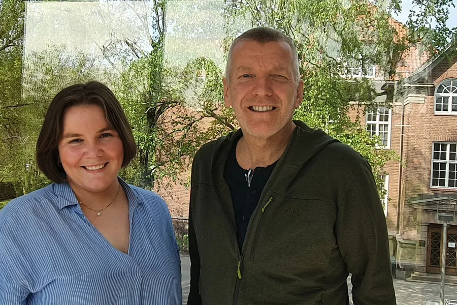 En smilende mann og kvinne står foran et gammelt murbygg.