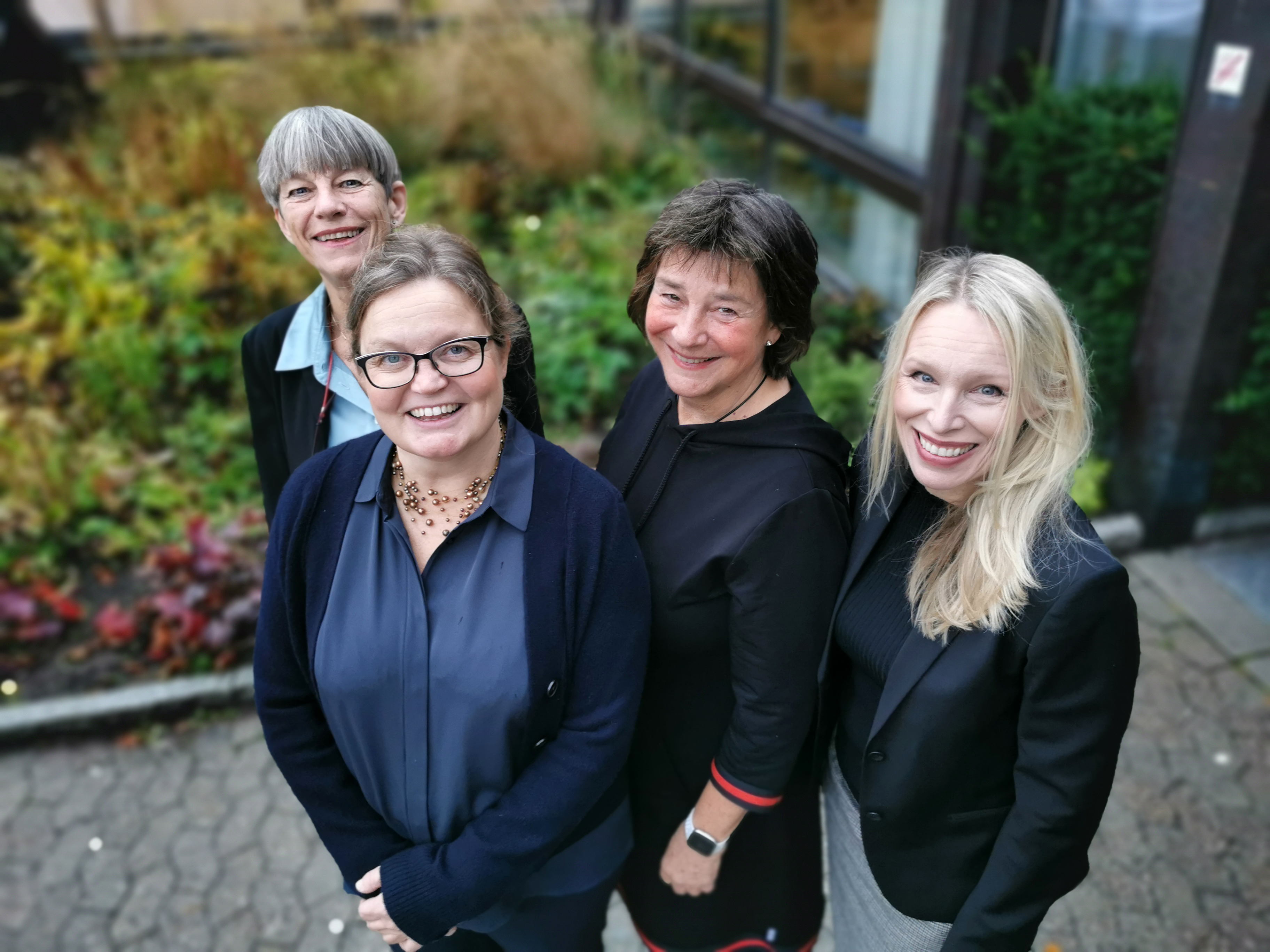 Disputanten står utenfor sykehuset med sine tre veiledere og smiler opp til fotografen