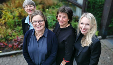 Disputanten står utenfor sykehuset med sine tre veiledere og smiler opp til fotografen