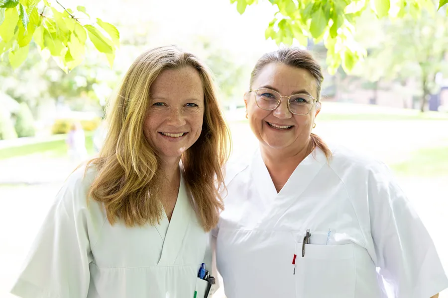 to kvinner i hvit uniform står ute blant trær