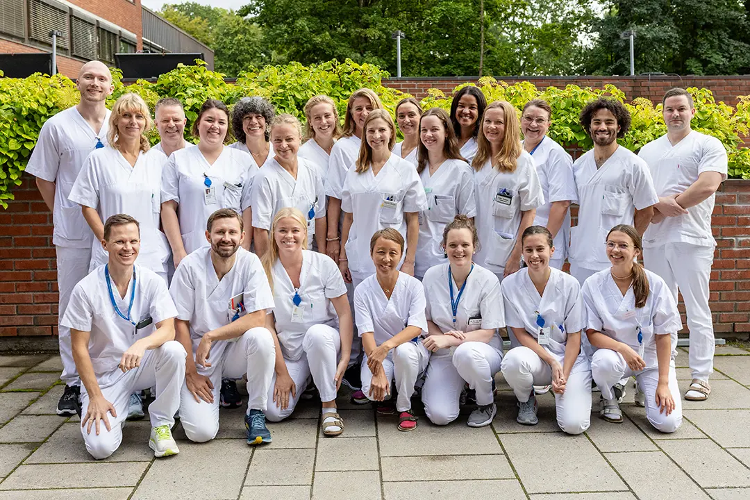 Flere personer kledd i hvitt foran en mur