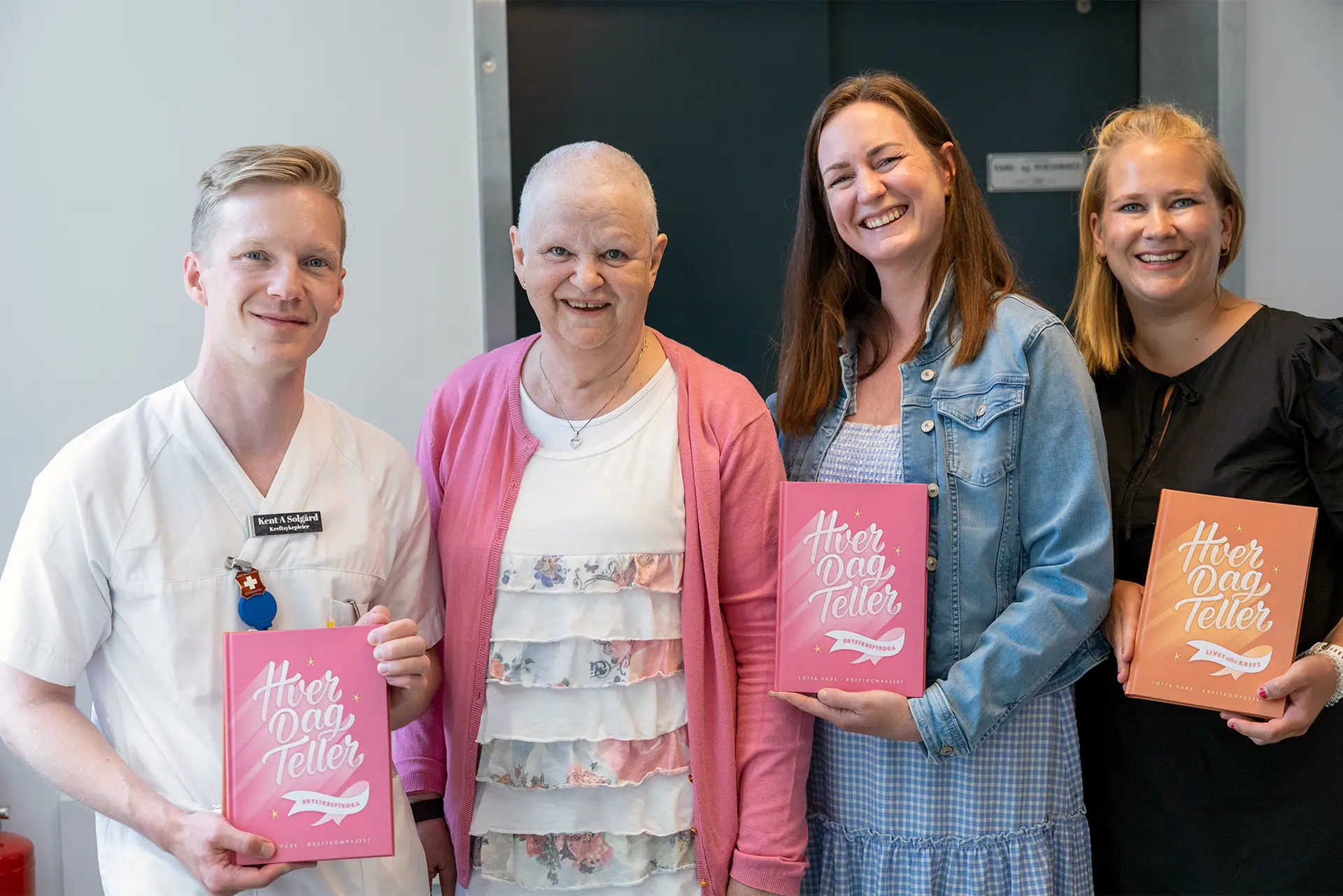 Fire smilende fjes. En mannlig fagsykepleier i hvitt, en eldre dame i rosa med kortklipt hår (kreftpasient) og to blide damer