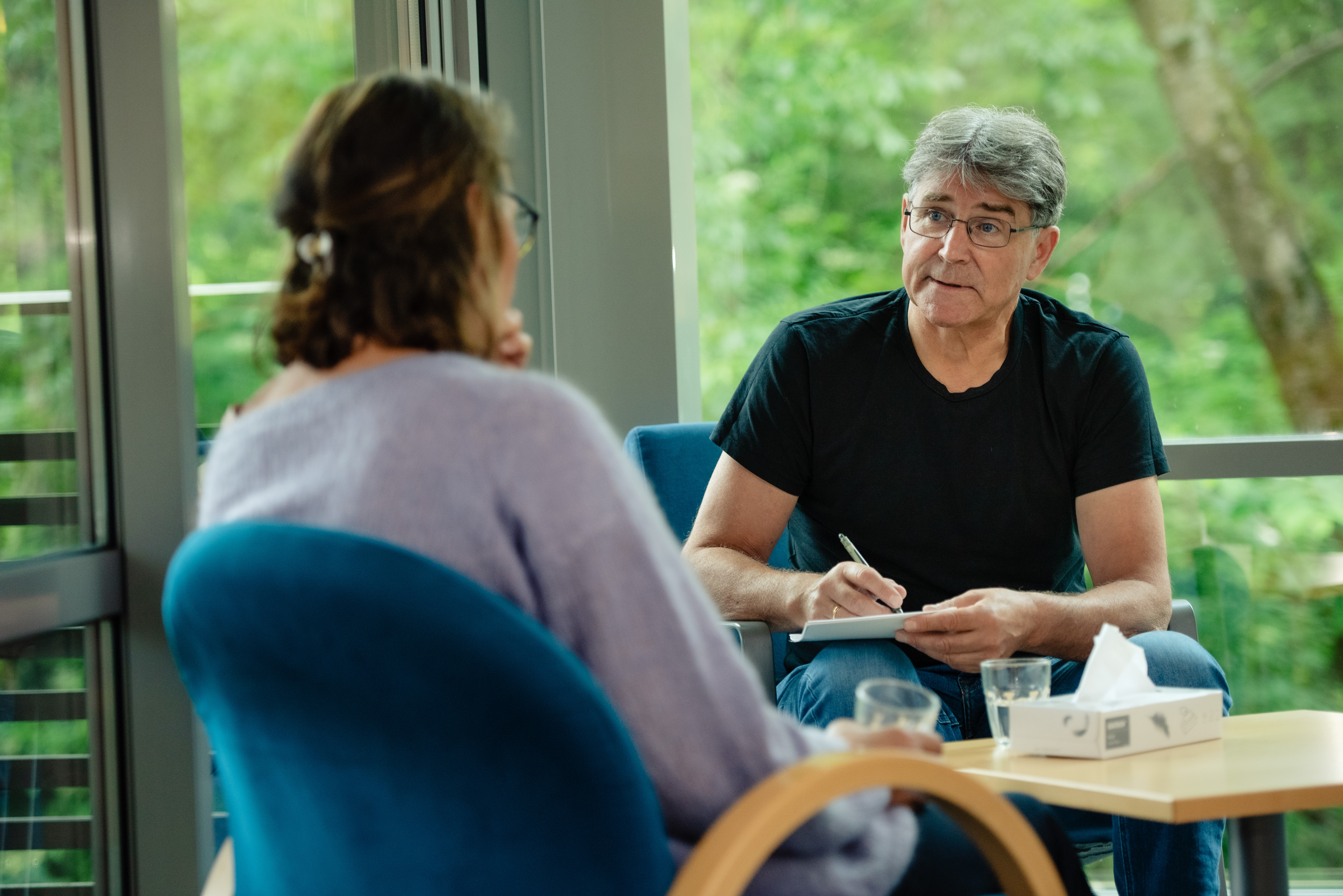 Mann noterer på en blokk mens han snakker med kvinne