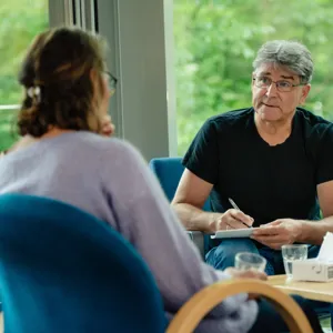 Mann noterer på en blokk mens han snakker med kvinne