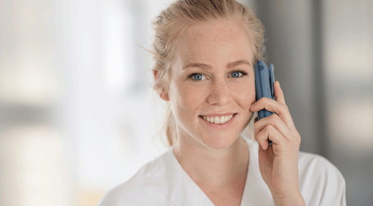 Kvinnelig sykepleier smiler mens hun snakker i telefon