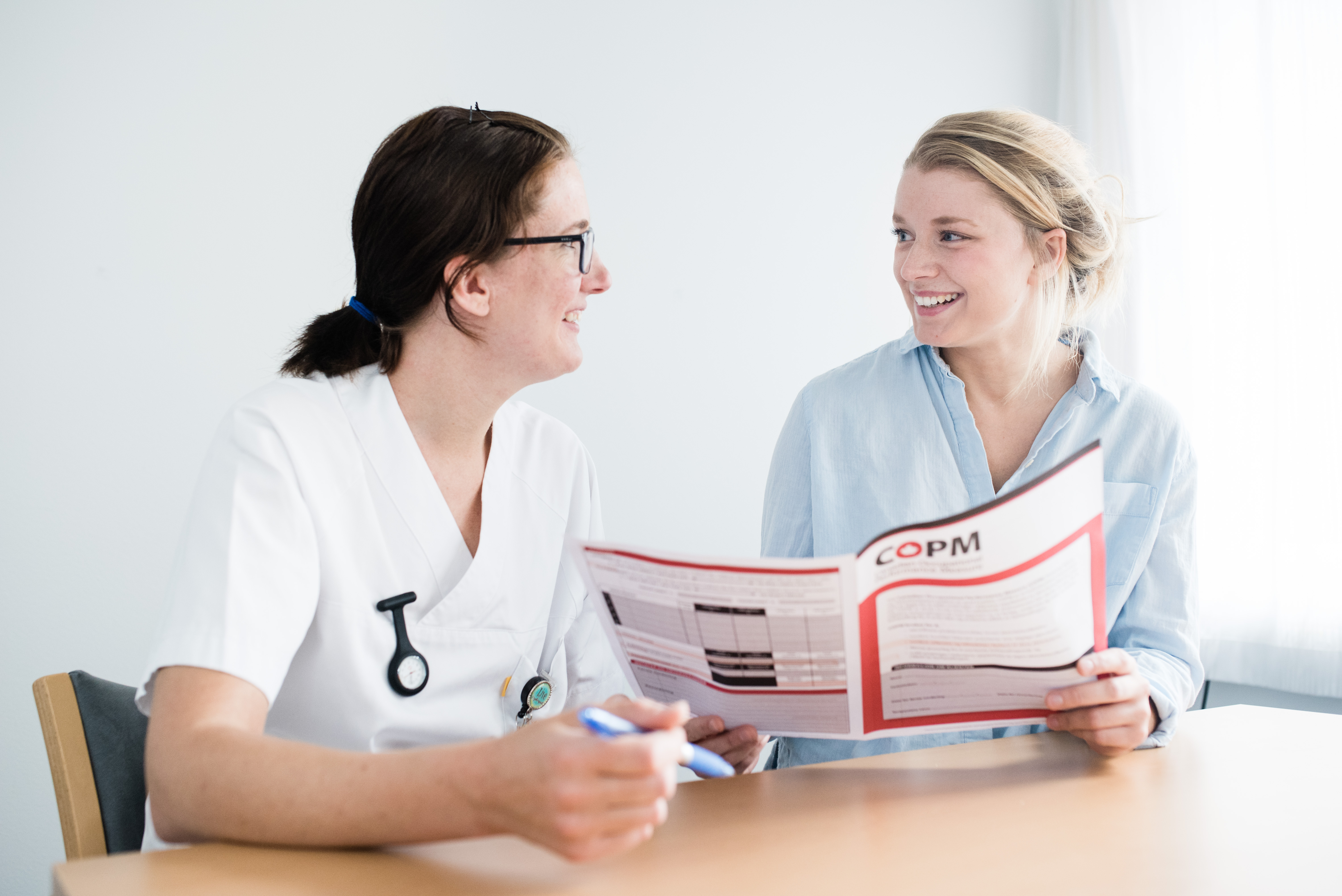 Kvinner i hvite frakker ser på en bok