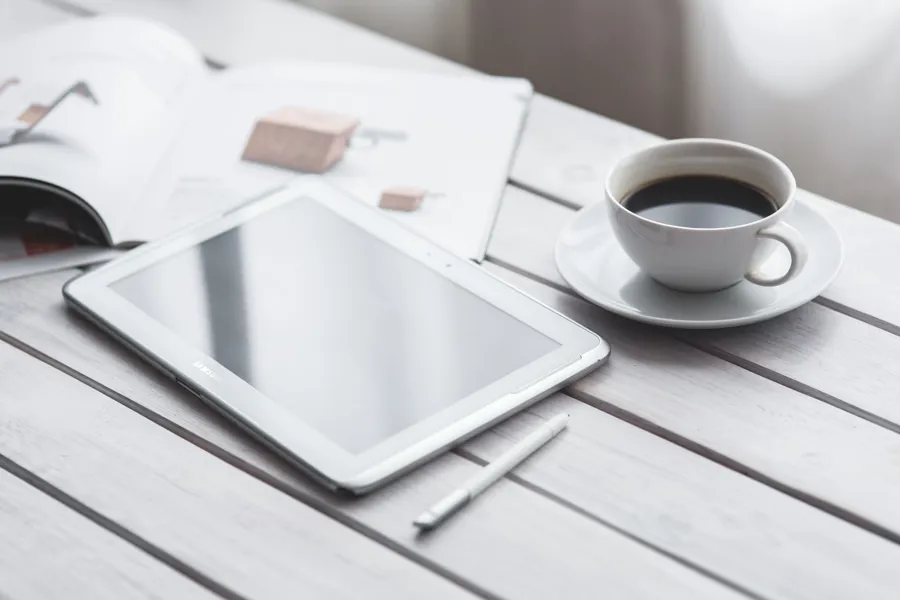 En tablett og en kopp kaffe