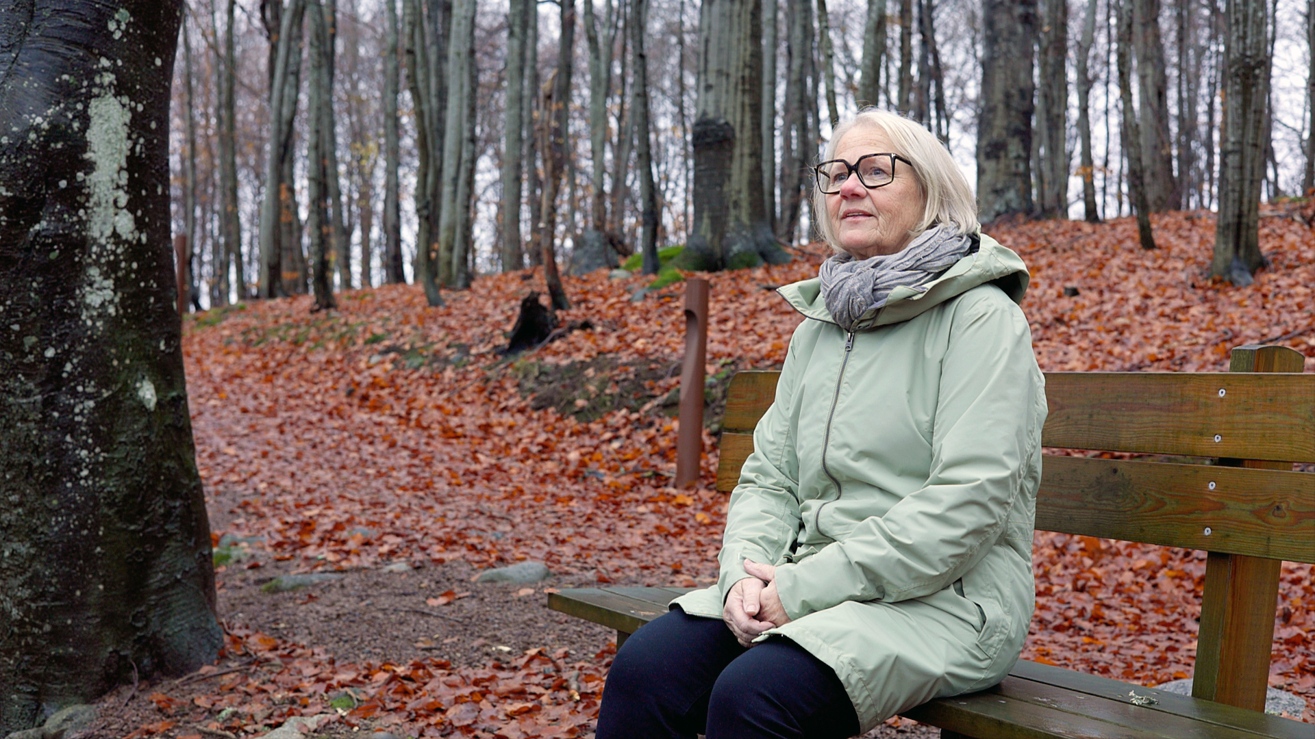 Dame som sitter på en benk i skogen