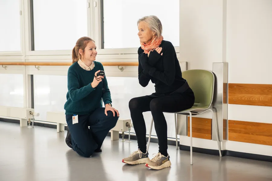 En person som sitter ved siden av en person som holder en telefon