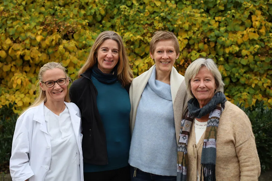 En gruppe kvinner som poserer for et bilde foran en busk