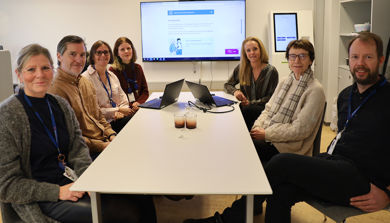 En gruppe mennesker som sitter rundt et bord med bærbare datamaskiner